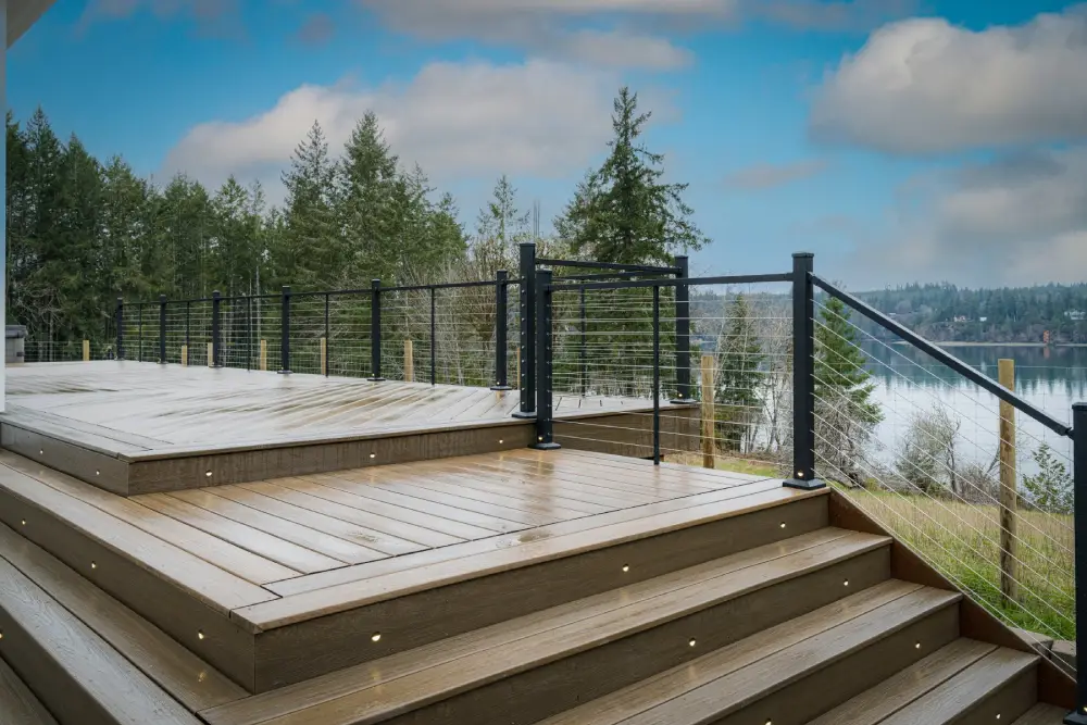 A modern outdoor deck with built-in lighting and cable railing, complementing a seamless door installation for a scenic lake view.